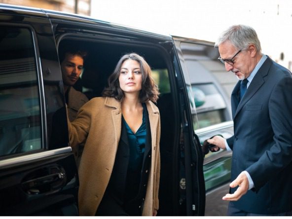 Woman getting out of a limousine with driver holding the door.