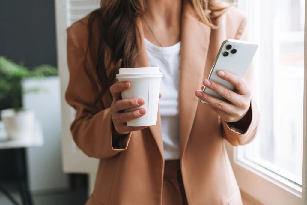 Woman with phone and coffee.