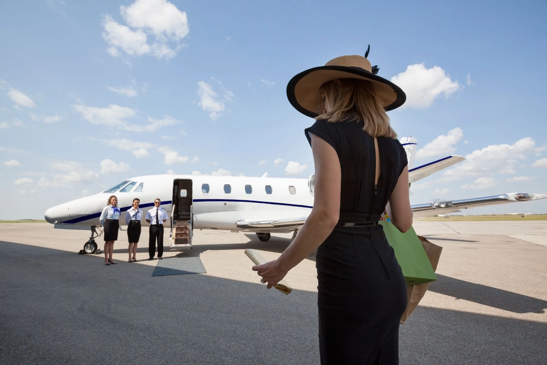 Woman walking towards private jet and crew.