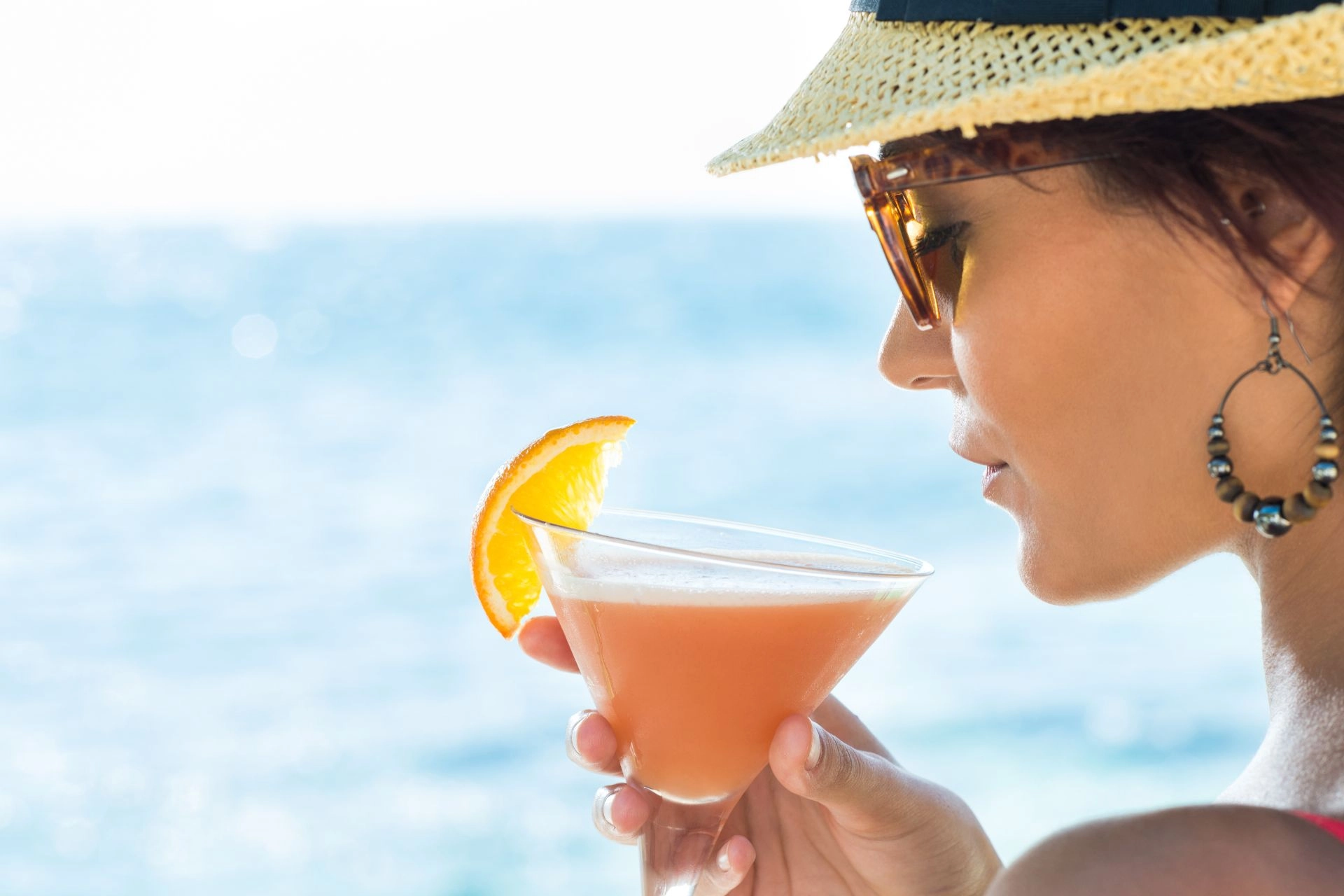 Woman enjoying a cocktail on the beach.