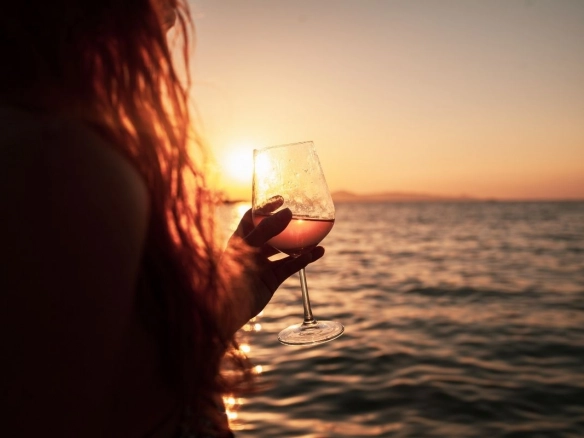 Woman with glas of wine at sea.