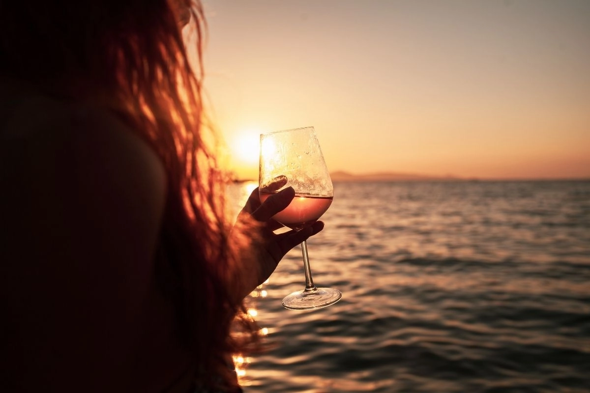 Woman with glas of wine at sea.